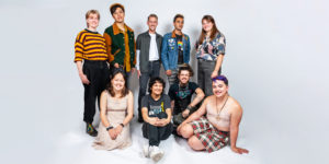 Studio portrait photograph of a diverse group of people sitting against a plain background.